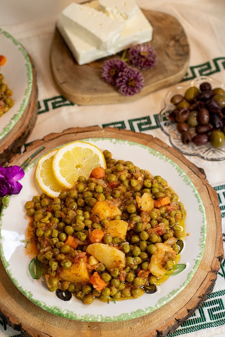 there is a plate of food with peas and lemons on the table next to it