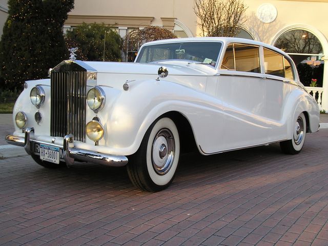 an old white car is parked on the street