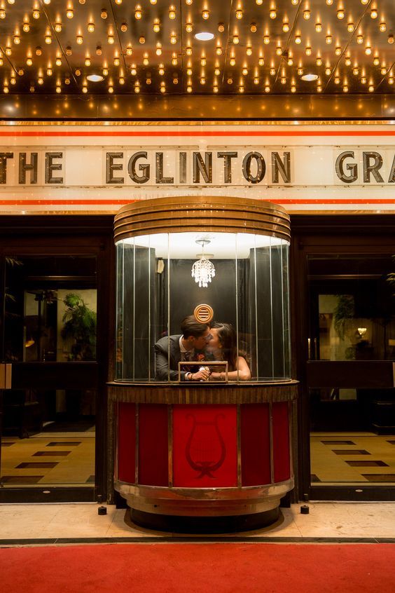 a person taking a photo in front of the egliinton gras building