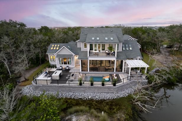 an aerial view of a house with a pool in the foreground and trees surrounding it