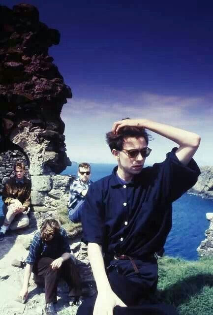 a group of people sitting on the side of a cliff next to water and rocks