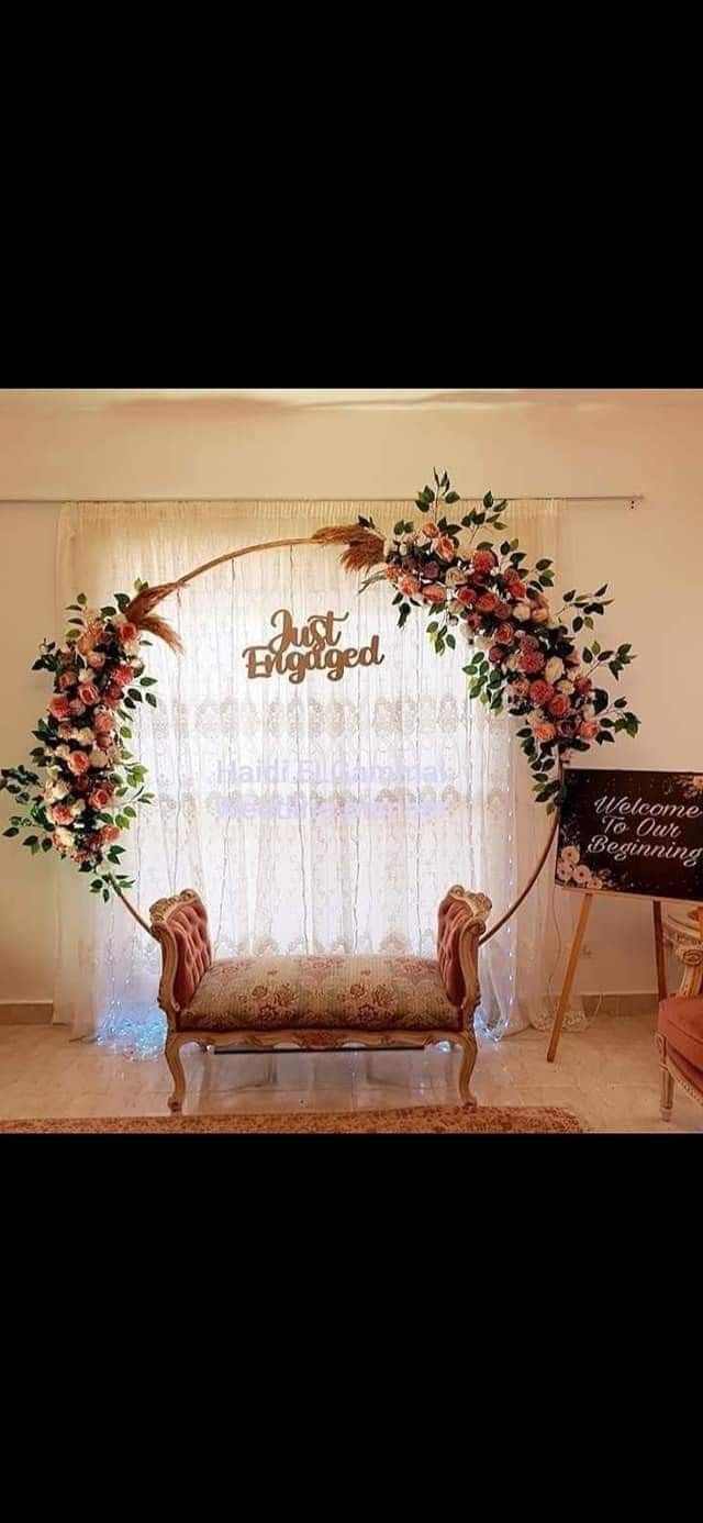 a couch sitting under a floral arch in front of a window