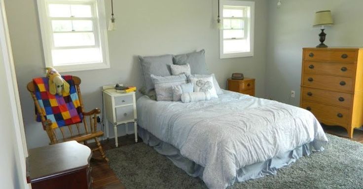 a bed sitting in a bedroom next to a dresser and window on top of a wooden floor