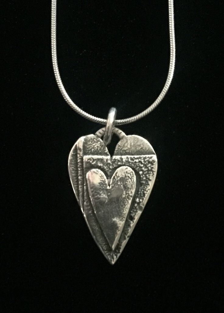 "This pendant consists of three layers of silver with a 5/8\" heart on top. The texture is a result of heating and reheating the metal almost to a melting point." Hand Forged Silver Heart Jewelry, Silver Heart-shaped Etched Necklace, Unique Silver Heart Charm Necklace, Unique Silver Heart Necklace With Charm, Unique Silver Heart Pendant Necklace, Etched Heart Silver Necklace, Heart-shaped Sterling Silver Soldered Necklace, Silver Hand Forged Heart Necklace, Hand Forged Silver Heart Necklace