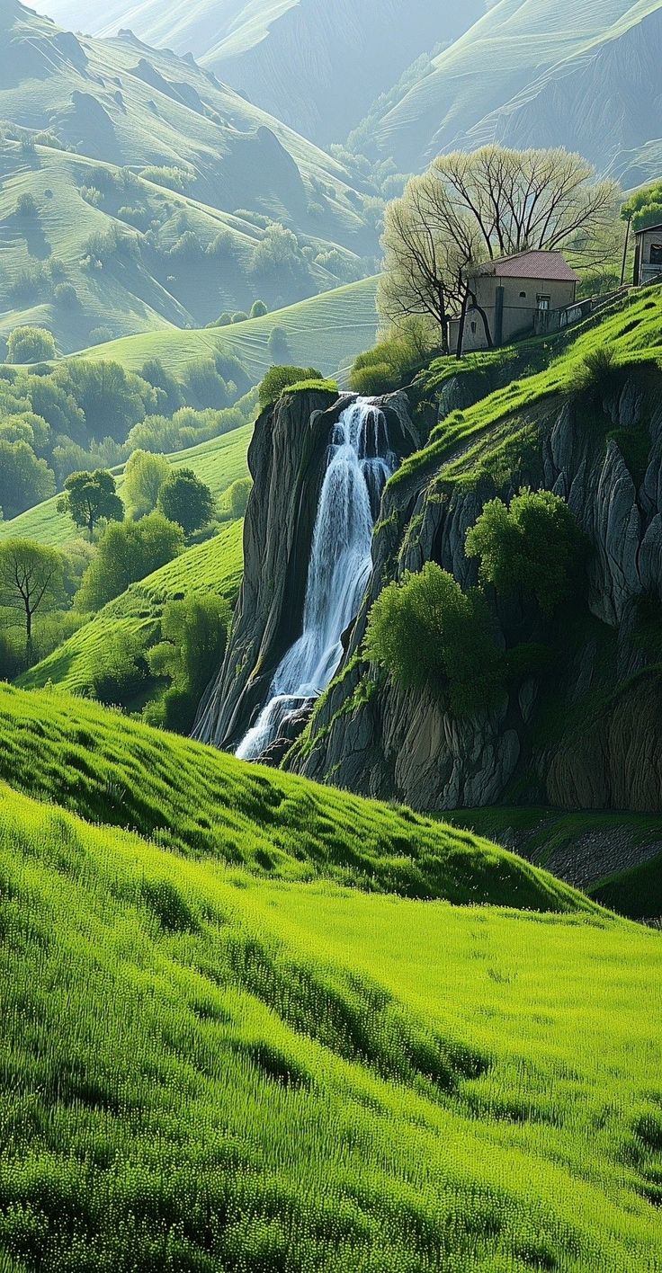 a house on top of a hill with a waterfall in the middle and green grass below