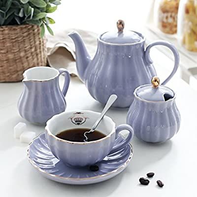 three tea cups and saucers with spoons on a white counter top next to a basket