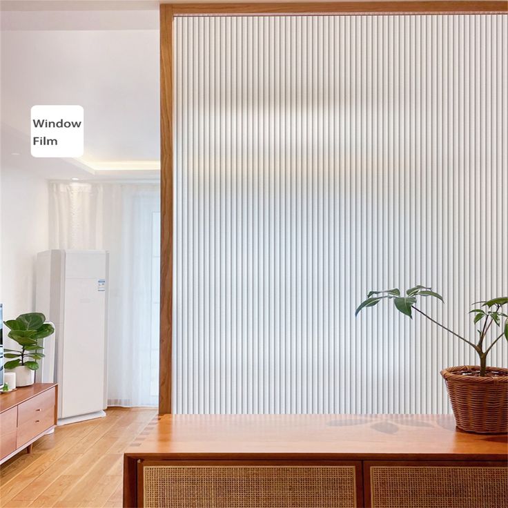 a living room with a plant on top of a wooden table next to a window