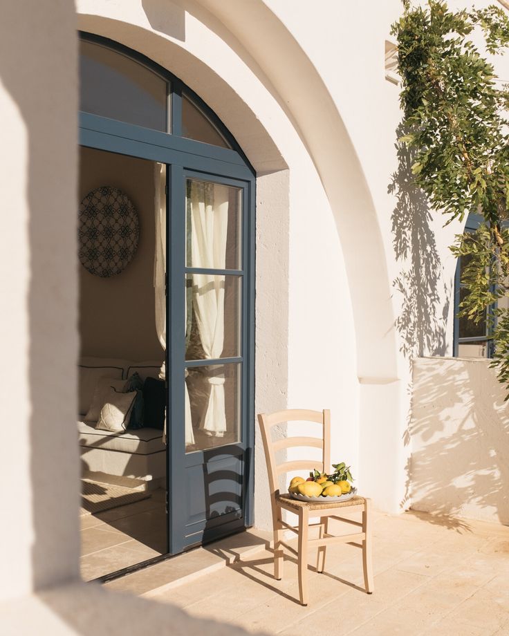 a wooden chair sitting on top of a patio next to a door with curtains over it