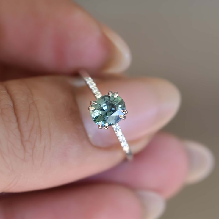 a woman's hand holding an engagement ring with a blue diamond in the center