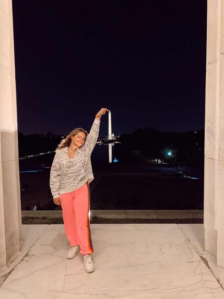 a woman posing for a photo in front of the lincoln memorial with her arms up