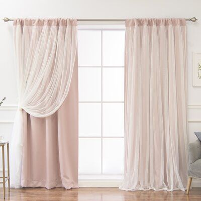 a living room with a couch, chair and window covered in pink drapes