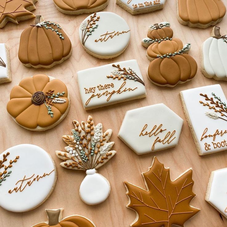 many decorated cookies on a table with autumn leaves and pumpkins in the background,