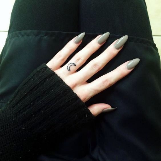 a woman's hand with grey manies and a crescent moon tattoo on it