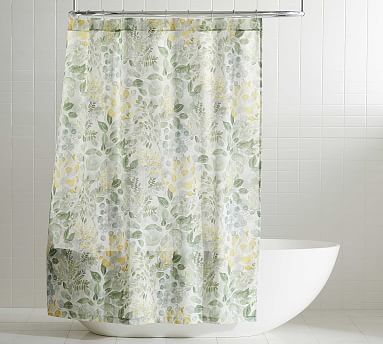 a shower curtain with green and yellow flowers on it in a white tiled bathroom area