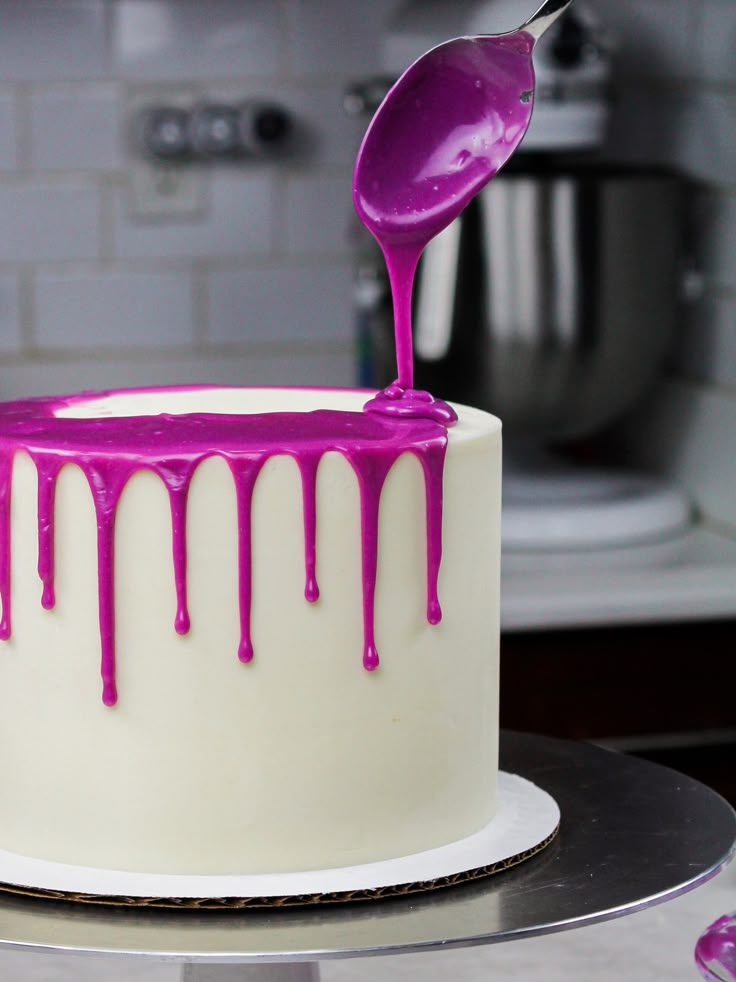 a white cake with purple icing on it and a spoon sticking out of the top