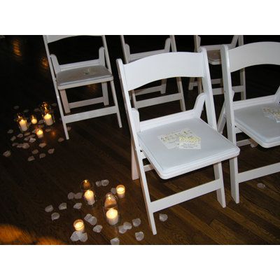 several white chairs with candles on the floor