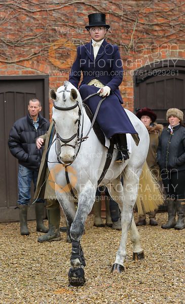 a man riding on the back of a white horse in front of people standing around