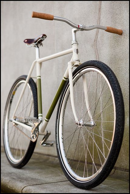 a white and green bike leaning against a wall with no wheel hubs on it