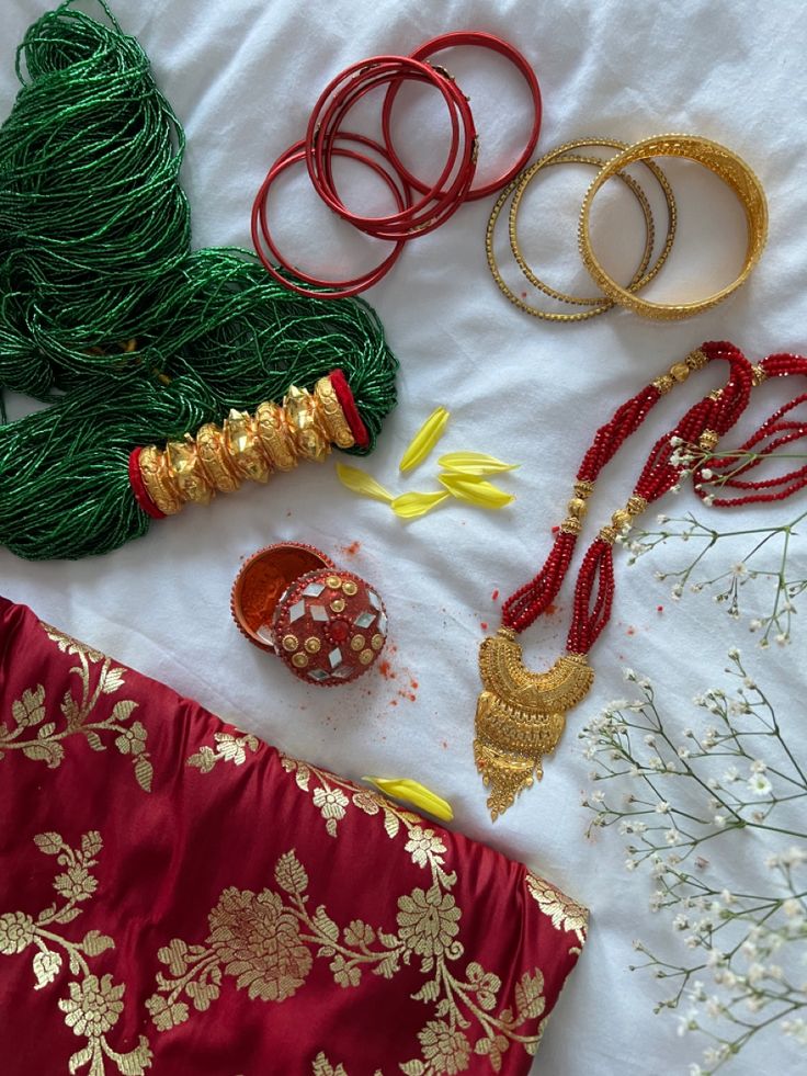 various bracelets and necklaces are laid out on a bed with white flowers in the background