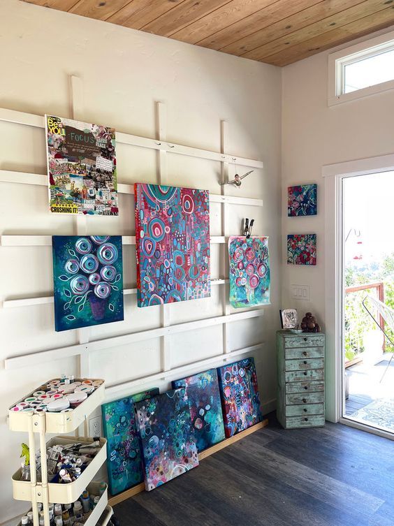 a room filled with lots of paintings on the wall next to a wooden floor and door