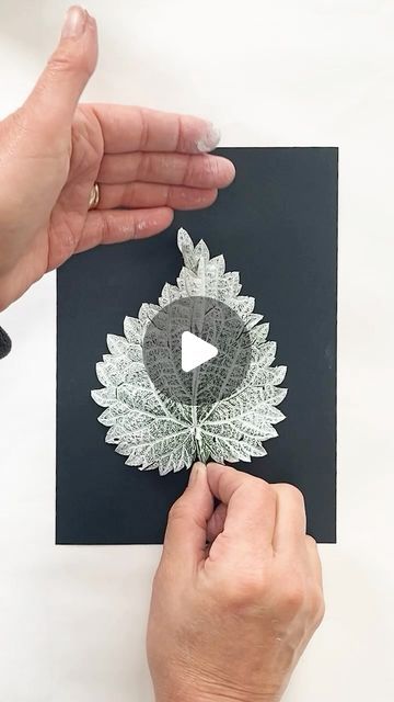 two hands are holding a piece of paper with an image of a flower on it