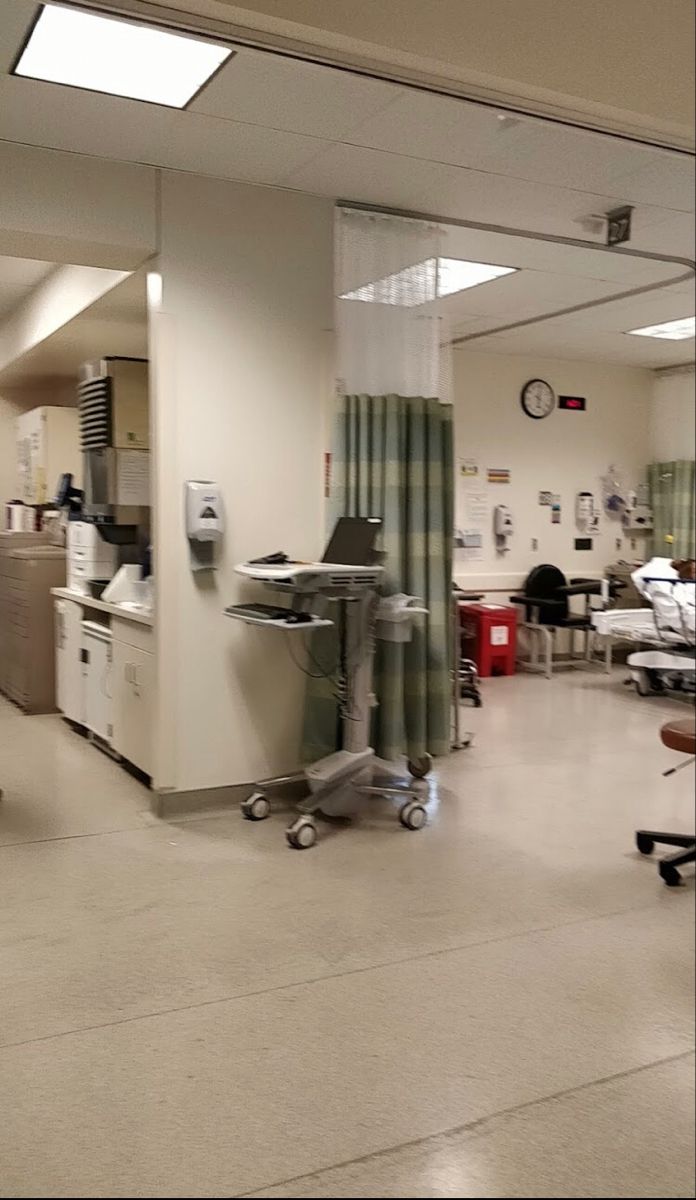 an empty hospital room with medical equipment in the background and people sitting at their desks