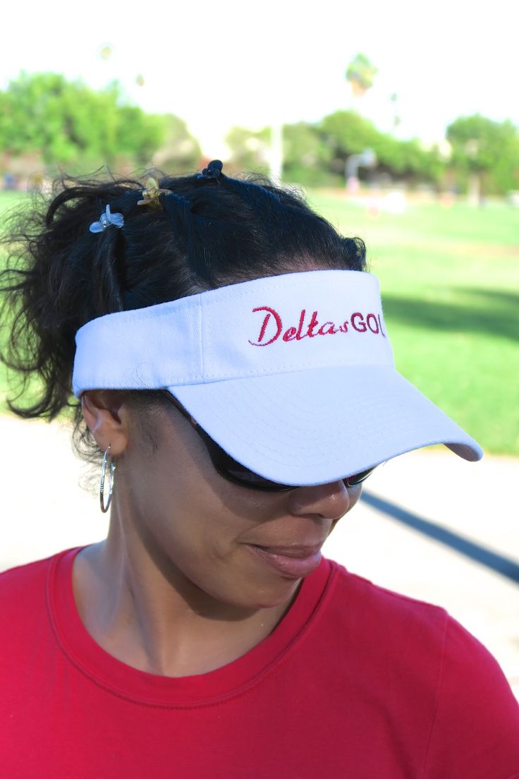 a woman wearing a red shirt and white visor with the word delta on it