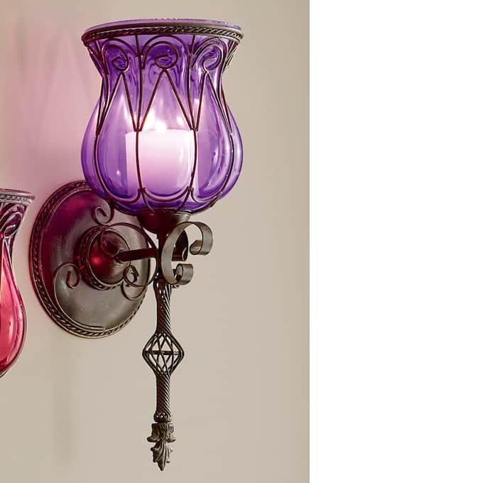 two purple and pink glass wall sconces hanging on a white wall next to each other