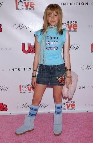 a woman in short shorts and boots standing on a pink carpet