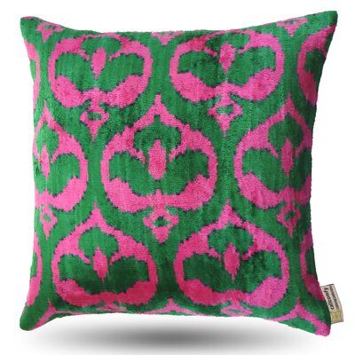 a pink and green pillow with an ornate design on the front, sitting on a white background