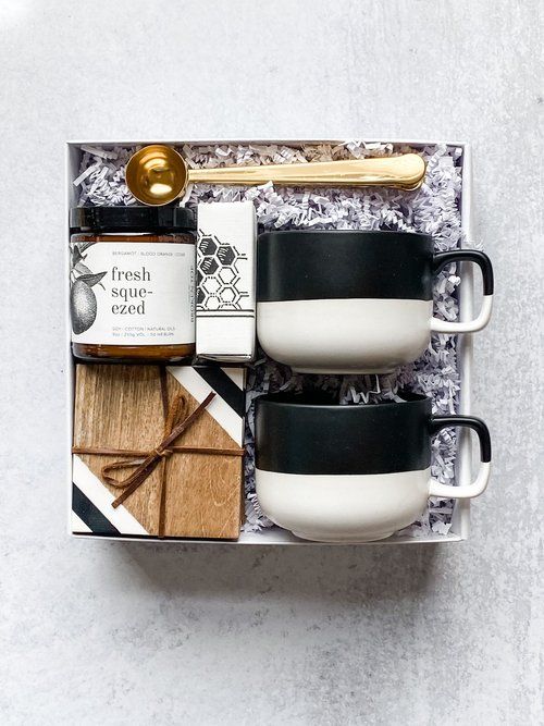 three coffee mugs in a gift box with spoon and crackers on the side