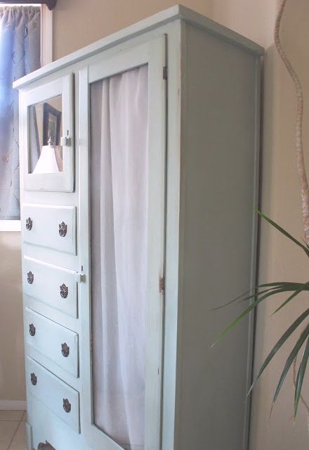 a white armoire sitting next to a potted plant