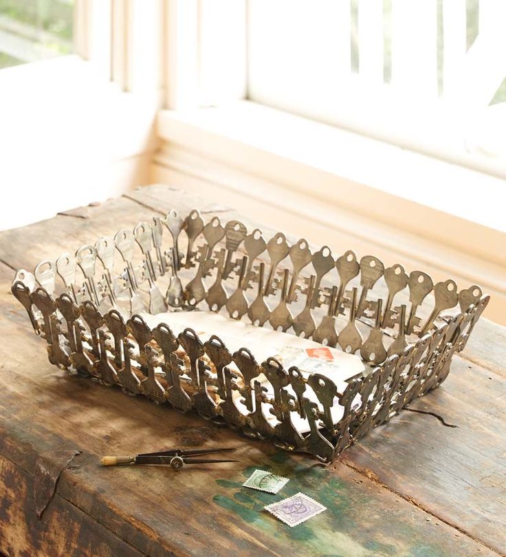 a metal basket sitting on top of a wooden table next to a pair of scissors