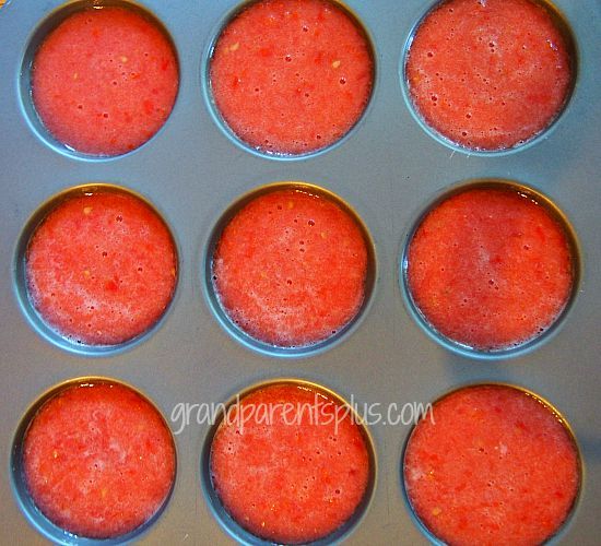 twelve red cupcakes in a muffin tin ready to be baked and eaten