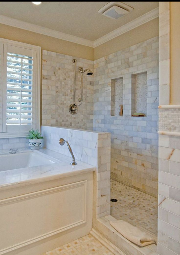 a bathroom with a large tub and white tile walls, along with a walk in shower