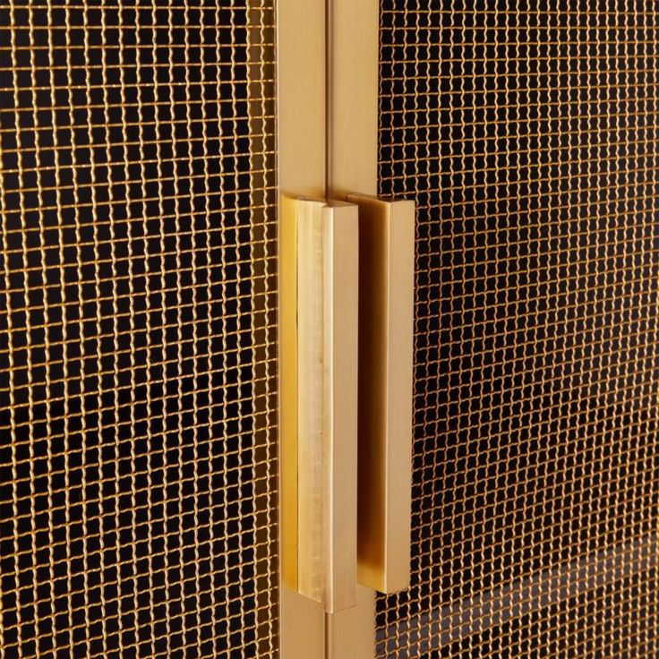 a close up view of a door handle on a wall with metal mesh behind it