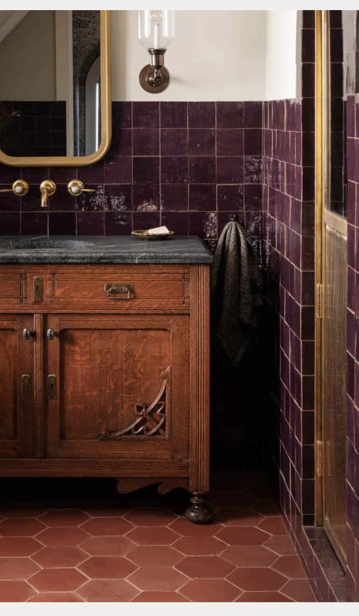 a bathroom with purple tiles and a wooden cabinet