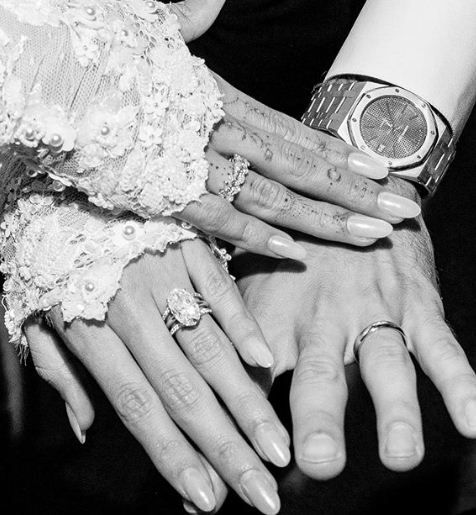 black and white photograph of two people holding each other's hands with rings on their fingers