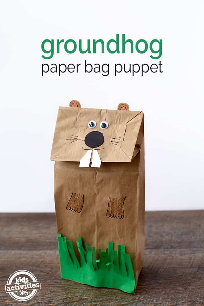 a paper bag that has grass in it and a bear face on the side, with text overlay reading groundhog paper bag puppet