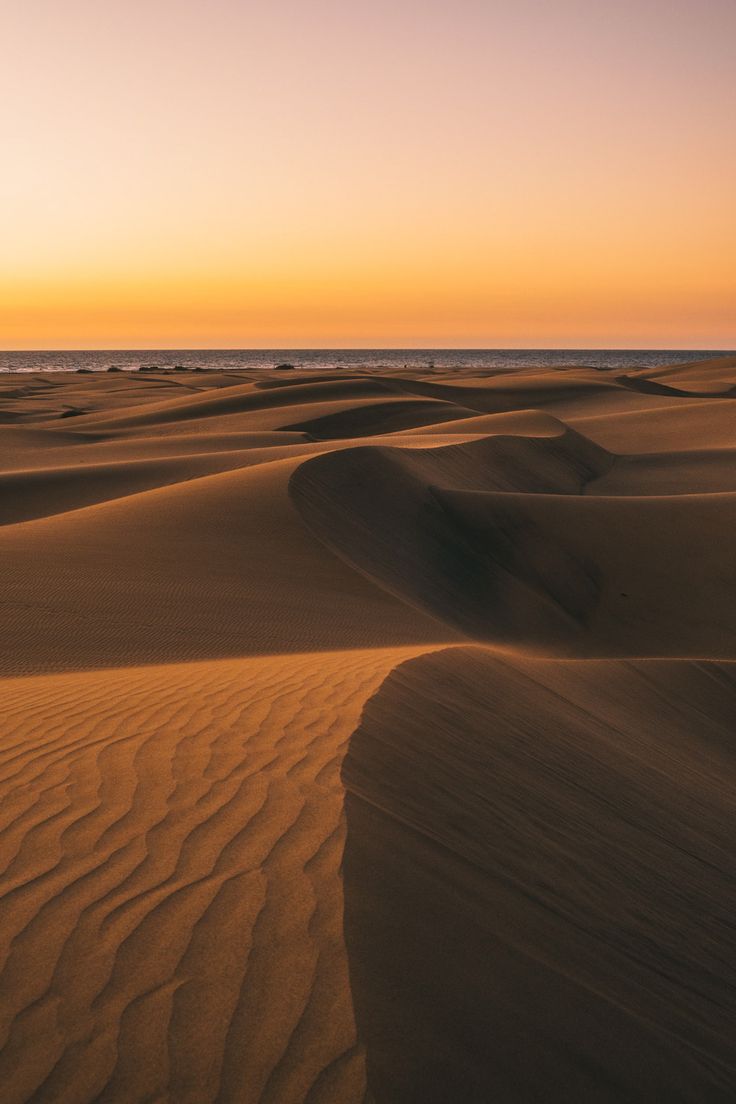 the sun is setting over some sand dunes