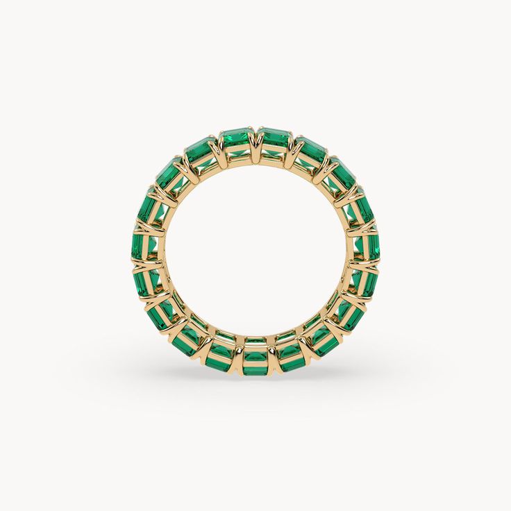 The Eden Eternity Ring Small captivates with its refined elegance and the impressive beauty of 4 mm lab-grown emeralds. Set in 14-karat recycled gold, one sparkling emerald is placed next to the other, creating a continuous band of radiant green. This ring is a true masterpiece, shining brilliantly from every angle and adding a subtle yet striking accent to your style. Luxury Green Emerald Stackable Ring, Luxury Stackable Emerald Cut Emerald Ring, Luxury Stackable Emerald-cut Emerald Ring, Fine Jewelry Green Emerald Cut Eternity Band, Stackable Emerald Ring In Yellow Gold, Green Emerald Eternity Band Fine Jewelry, Yellow Gold Emerald Jewelry With Half Eternity Detail, Green Emerald Cut Eternity Band, Elegant Green Stackable Eternity Band