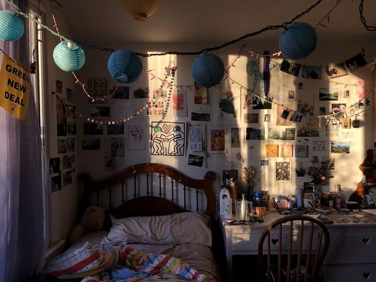 a bedroom with many pictures on the wall and lights hanging from the ceiling over the bed