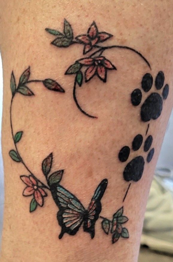 a woman's leg with a butterfly and flower tattoo design on the calf area