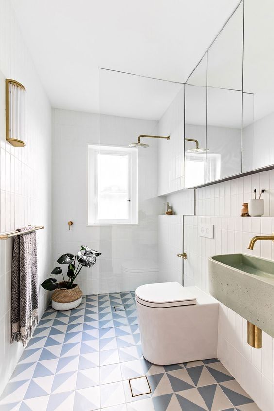 a bathroom with blue and white tiles, gold fixtures and a plant in the corner