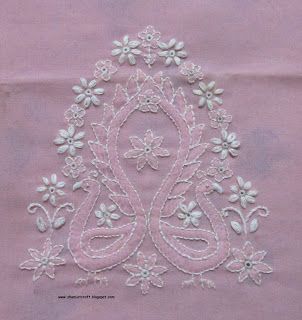 an embroidered design on pink fabric with white flowers