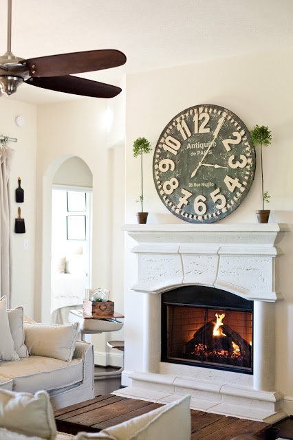 a living room filled with furniture and a large clock on the wall above a fireplace