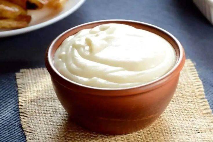 a bowl filled with cream sitting on top of a table next to other food items