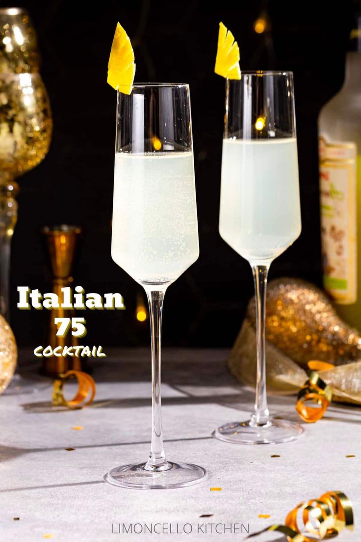 two champagne flutes with lemon wedges in them sitting on a table next to confetti