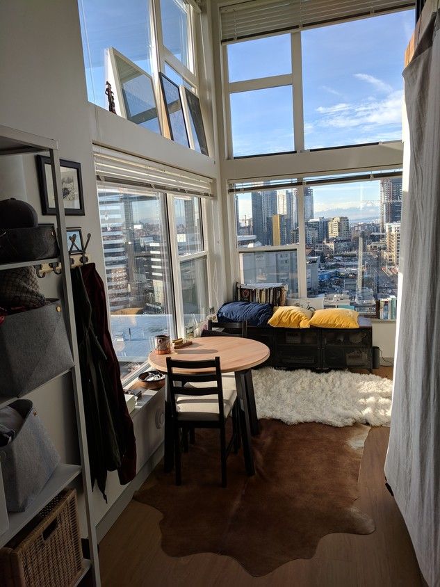 a living room filled with furniture next to large windows and a view of the city