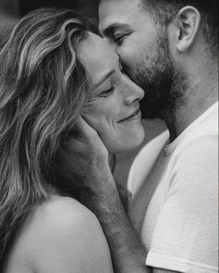 black and white photograph of a man kissing a woman's face with long hair